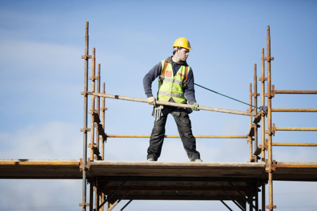 Construction worker setting up scaffolding.