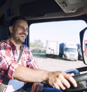 Professional middle aged truck driver in casual clothes driving truck vehicle going for a long transportation route.