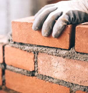 Close up of industrial bricklayer installing bricks on construction site