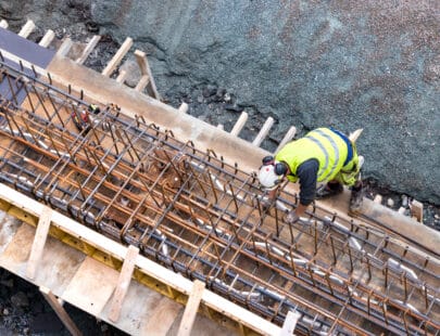 Betongarbetare Tromso, Norway - August 3th, 2018: Top view of a builder worker working on a concrete construction under the bridge of Tromso, Norway