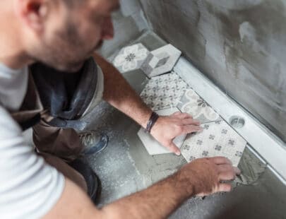Tiler installing tiles on the bathroom floor High angle image of male builder installing tiles on the bathroom floor