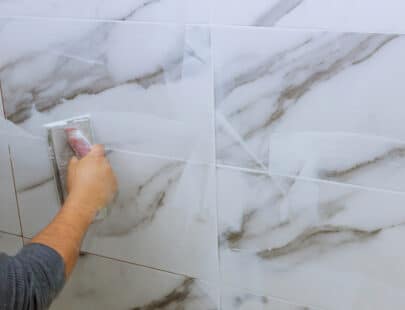Male hand with the rubber applies grout on a seam between tiles Grouting tiles male hand with the rubber applies grout on a seam between tiles