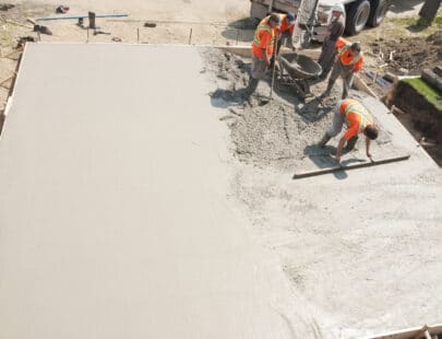 Concrete Crew Crew of concrete workers pouring and leveling a garage pad. Half of the pad is done and would make great copy space.