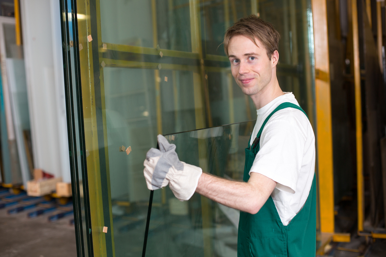 Glazier in workshop handling glass Glastekniker